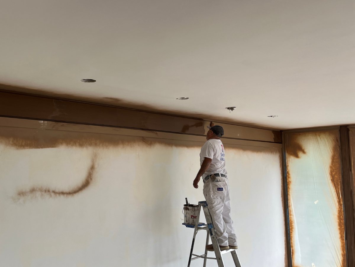 A Reyes Pro Painting crew member cutting in a ceiling line during an interior repaint